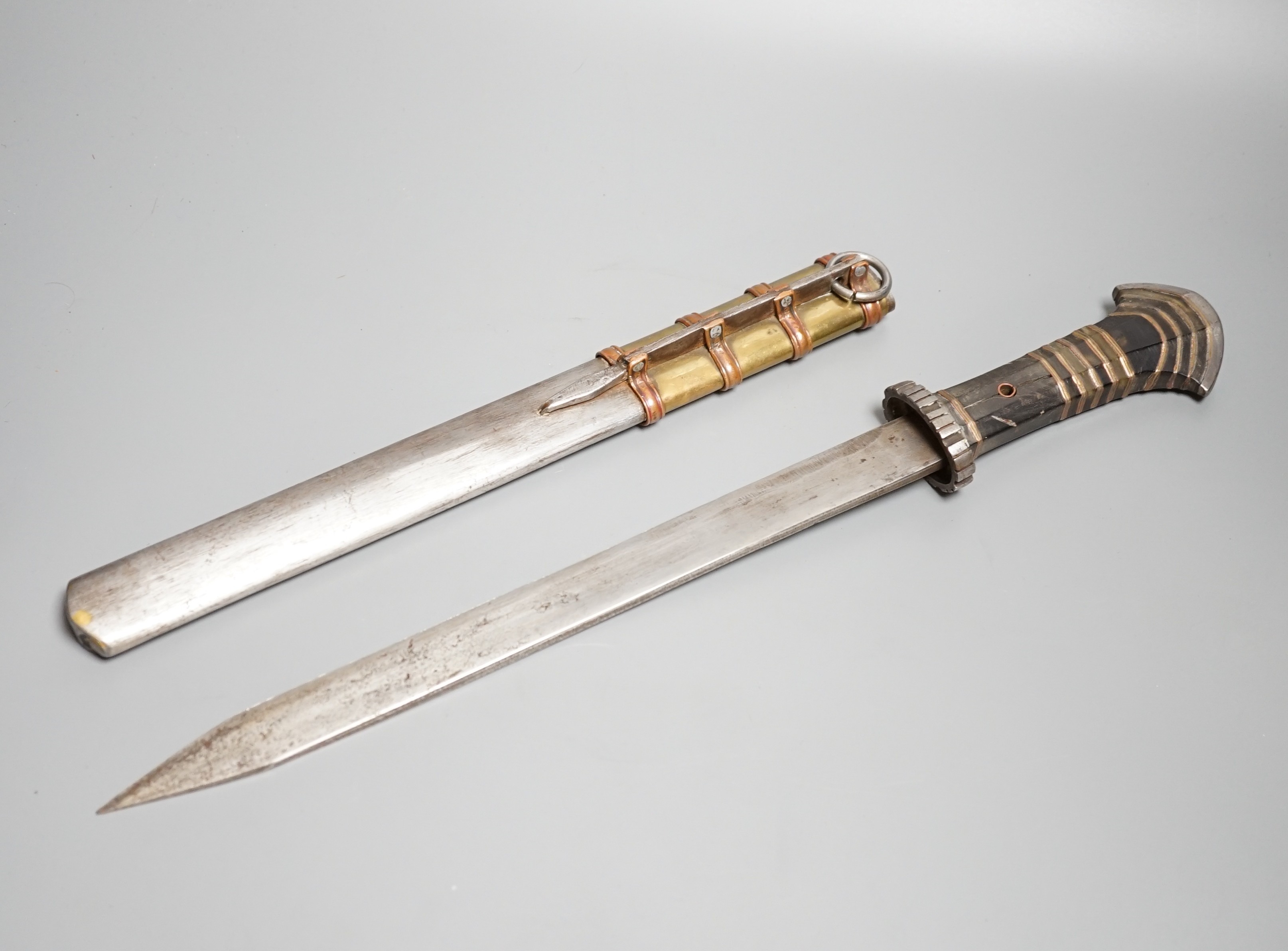 A large Tibetan dagger, early 20th century, horn handle with layers of copper and brass, iron pommel, guard and sheath with copper and brass mounts, length 46cms